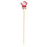 A wooden skewer with a small, smiling Santa Claus figure at the top, featuring a red suit, white beard, black boots, and raised arms. This festive decorative pick is perfect for holiday party supplies and photographed against a white background.