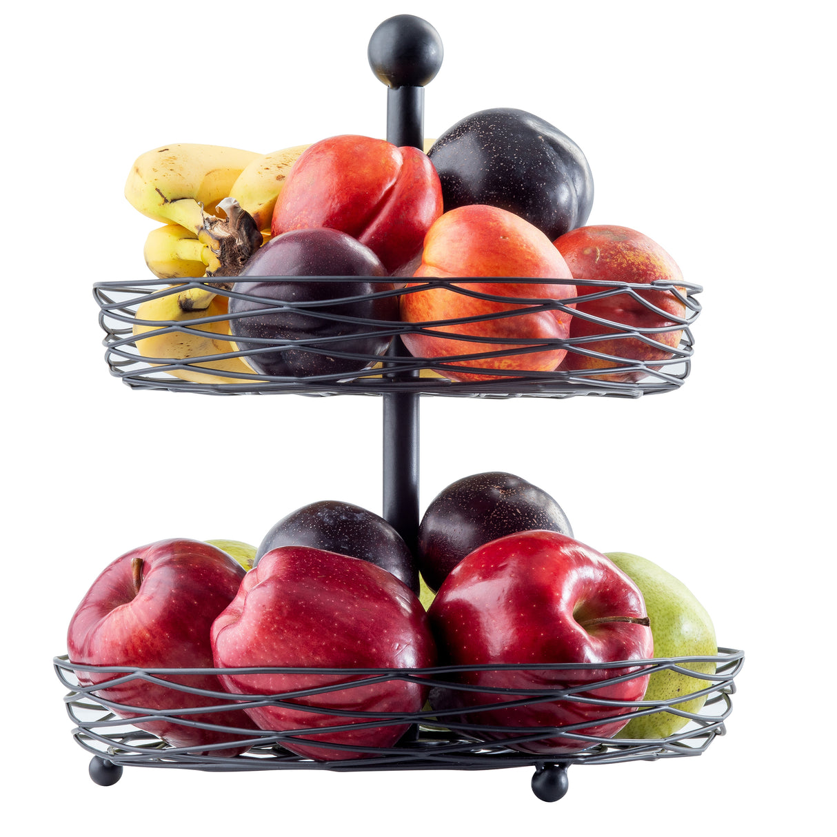 A two-tiered black steel display basket holds bananas, plums, nectarines, red apples, green apples, and two dark purple fruits. The fresh, colorful fruits are beautifully arranged against a white background.