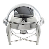 A shiny, stainless steel chafer with a domed lid featuring a glass window. The dish sits on four arched legs with a fuel holder underneath. Its reflective surface and modern design make this dripless roll top chafer ideal for serving hot food at events.