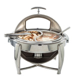 A shiny stainless steel chafer with a domed lid is open, revealing two sections: one with cubed chicken and tongs, the other with creamy soup topped with grated cheese. A serving spoon rests in the creamy section of this elegant serving dish.
