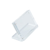 A clear Acrylic Sign Holder by TableCraft, this display stand features a slanted rectangular frame with inset magnets and visible corner screws, perfect for holding cards or signs on any tabletop. Photographed on a plain white background.