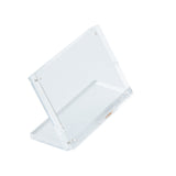A clear, rectangular Acrylic Sign Holder by TableCraft is shown at an angle on a white background. Featuring inset magnets and a slanted design with visible corner screws, it’s ideal for displaying photographs, signs, or brochures.