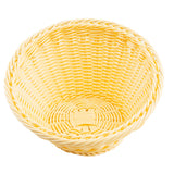 A round, empty, light yellow handwoven basket is shown from above. The basket has a braided rim and a tightly woven pattern, with the base featuring a slightly different weave for added support. The background is plain white.