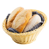 A light handwoven basket holds three oval loaves of crusty bread, resting on a dark gray and white striped cloth. The rustic bread is lightly floured, while the white background highlights the basket and its contents.