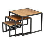 Three wooden nesting tables with square powder coated steel frames are stacked together. Each table features an acacia wood top with a natural finish, and the tables fit neatly underneath one another, showcasing a modern, minimalist design.