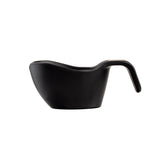 A matte black melamine sauce boat with a modern, curved shape and an ergonomic handle, photographed on a white background. The wide spout and stackable design add to its sleek, minimalist appeal.