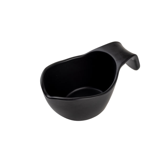 A matte black ceramic sauce boat with a rounded body and integrated, curved handle, shown angled on a plain white background. The thick, ergonomic handle and slightly tapered spout make pouring easy. Stackable for convenient storage.