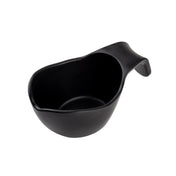 A black, asymmetrical TableCraft sauce boat with a curved handle on one end, photographed on a white background. The cup has a smooth matte finish and an organic, irregular shape, giving it a modern and minimalist appearance.