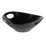 A glossy black, oval-shaped melamine serving bowl with asymmetrical, sloping sides. This modern Frostone Collection serving bowl features two circular cutout handles and a smooth, reflective surface. Dishwasher safe for easy cleaning.