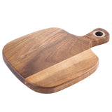 A rectangular TableCraft bread board crafted from Acacia wood with rounded edges, a smooth finish, and a handle featuring a circular metal ring for hanging. The visible wood grain highlights natural color variations. Set against a white background.