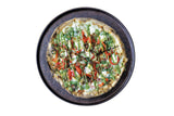 A whole vegetable pizza from the Lunara Collection rests on a dark melamine platter, topped with green and red bell peppers, onions, and melted cheese, drizzled with a dark sauce, viewed from above on a white background.