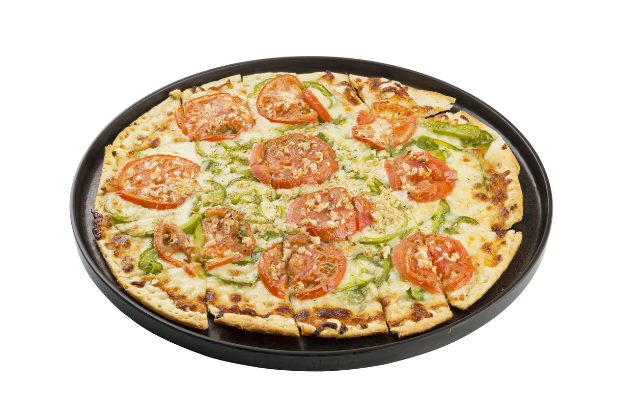 A whole vegetable pizza on a black round serving tray, sliced into pieces. The thin-crust pizza features tomato slices, green bell peppers, onions, cheese, and bits of garlic or breadcrumbs, all set against a white background.