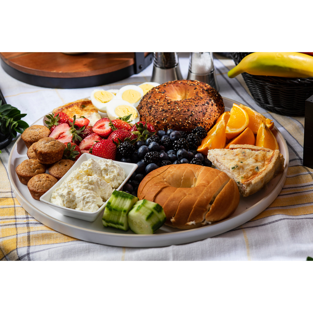 A breakfast platter featuring bagels, fruit, muffins, eggs, herbed cheese spread, and quiche is beautifully arranged on a Europa Collection Serving Tray—a stylish melamine serving tray that’s both elegant and dishwasher safe.