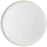 A round, shallow plate filled with smooth, white yogurt sits atop a white round serving tray from the Europa Collection. Photographed from above, the plate’s light beige rim frames subtly uneven yogurt with minor bubbles and ripples.
