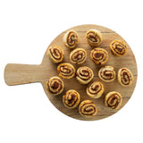 A round Serving Paddle from the Timber Melamine Collection holds 17 small cinnamon roll pastries in loose rows. Shot from above on a white background, the rolls display visible cinnamon swirls and a golden-brown color.
