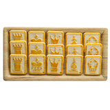 A wooden serving tray from the Timber Melamine Collection holds twelve rectangular cookies, each embossed with chess piece designs: rooks, kings, queens, pawns, and bishops. The cookies have a light golden crust with darker detailing.