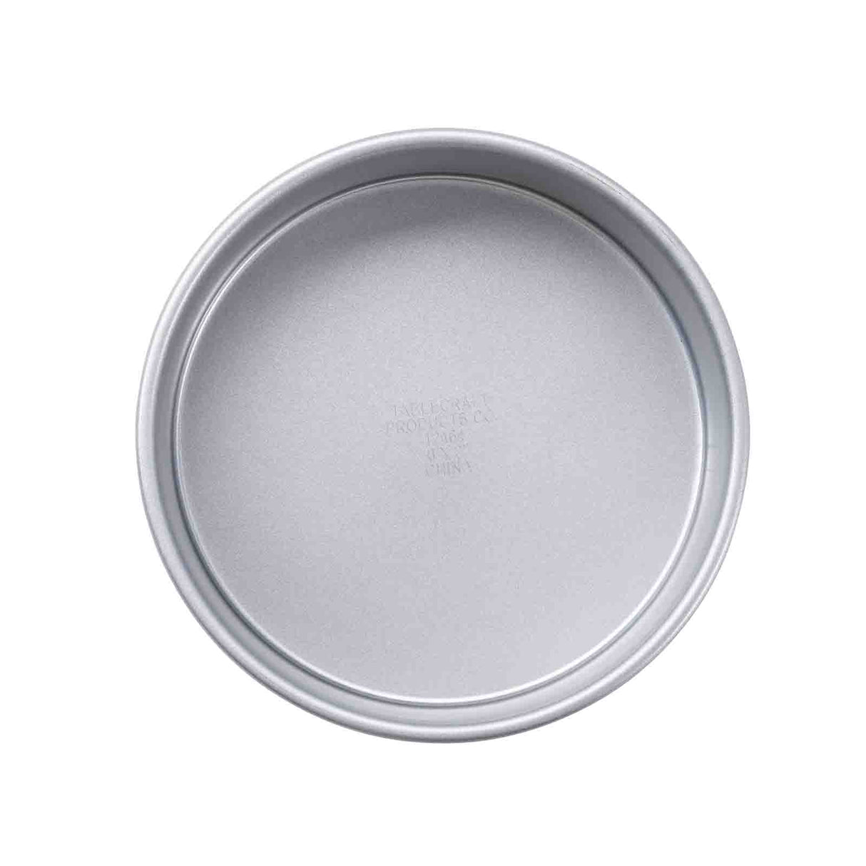 A round, non-stick cake pan with smooth sides and a flat bottom is shown from above against a white background. Faint embossed text appears in the center of this simple, unadorned silver pan.