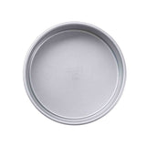 A round, non-stick cake pan with smooth sides and a flat bottom is shown from above against a white background. Faint embossed text appears in the center of this simple, unadorned silver pan.