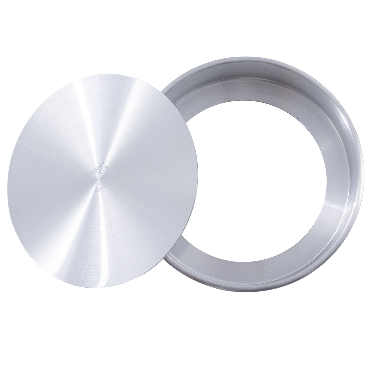 A round aluminum cheesecake pan by TableCraft is shown with a smooth, shiny finish. Its flat, circular lid rests diagonally on top, revealing the empty interior of the silver metal pan.
