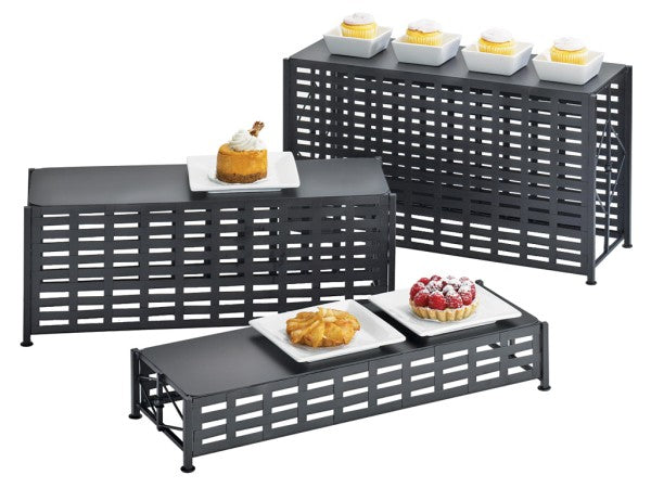 Three black BPA free lattice design metal display risers of varying heights hold small white plates with pastries and cupcakes. The arrangement showcases desserts on each tier, including cupcakes, a tart, a pastry, and a berry dessert.