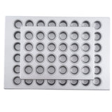 Two rectangular aluminized steel muffin pans with multiple small, round wells are stacked together. The smaller mini muffin pan rests on top at a slight angle, both pans appearing clean and unused.