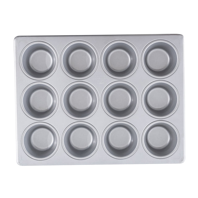 A clean, silver muffin pan with a non-stick surface, featuring twelve round cups in a 3 by 4 grid. The pan is empty and viewed from above against a white background.