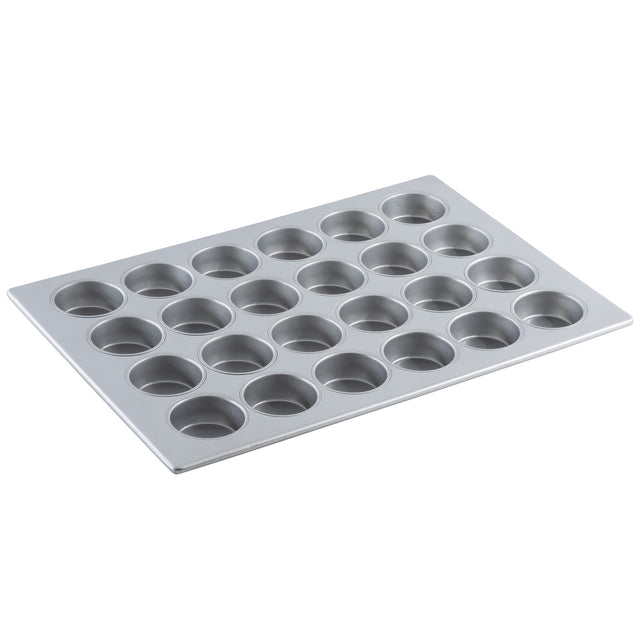 A silver non-stick muffin pan with 24 round cups arranged in a 4 by 6 grid, set on a white background. The tray is angled slightly, highlighting the cup depth and smooth cupcake pan surface.
