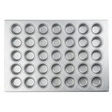 A silver non-stick cupcake pan with 48 evenly spaced round wells arranged in a grid pattern, photographed from above on a white background. The muffin pan features smooth edges and a shiny, metallic surface.
