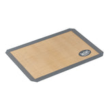 A rectangular half size silicone baking mat with a tan center and dark gray border, lying flat on a white background. The mat has a small round logo in one corner. Ideal for lining baking sheets for nonstick cooking.