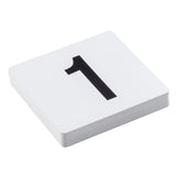 A stack of white PVC number cards lies on a white surface. The top card displays a large, bold black number 1 centered on it. The visible edges reveal multiple table numbers beneath the top card.