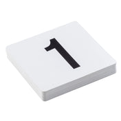 A stack of white PVC number cards lies on a white surface. The top card displays a large, bold black number 1 centered on it. The visible edges reveal multiple table numbers beneath the top card.