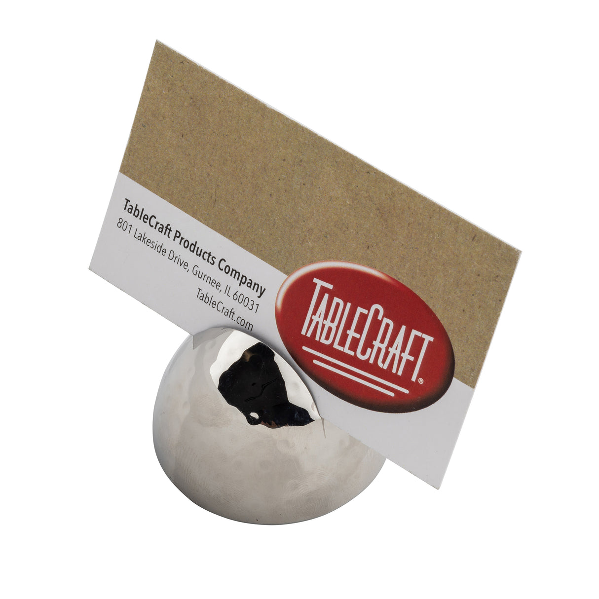 A metallic, dome-shaped card holder with a silver hammered pattern displays a brown business card for TableCraft Products Company, featuring a red and white logo and printed contact information against a white background.