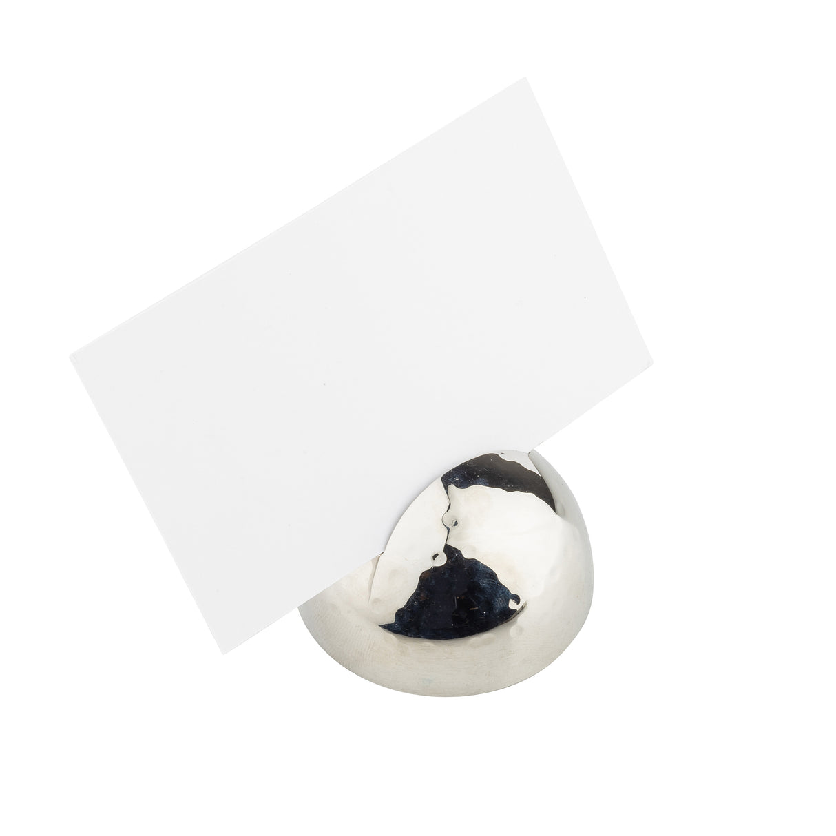 A blank white card is held upright by a silver hammered pattern card holder—a smooth, shiny sphere of stainless steel—against a plain white background. The reflective surface displays light and subtle reflections.