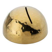 A shiny, hammered brass dome with a hammered pattern and a single narrow slot on top, resembling a minimalist piggy bank or decorative card holder. The surface reflects light with an uneven, dimpled texture, and the slot runs front to back.