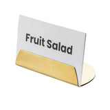 A white card labeled Fruit Salad in bold black letters is held upright by a gold coated stainless steel TableCraft Products Half Moon Card Holder. The background is plain white, and the card and holder are viewed at a slight angle from the front.