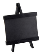 A small black chalkboard sits on a matching miniature wooden easel, both framed with thick black borders. This TableCraft tabletop board sign is empty and tilted slightly to the right, set against a plain white background.