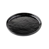 A round, black ceramic serving plate with a slightly raised edge and a glossy, textured surface is shown on a white background. The plate appears empty and has a simple, minimalist design ideal for modern table settings.