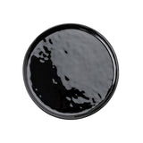 A round, glossy black TableCraft serving plate is shown from above against a white background. The plate has a smooth, reflective melamine surface with subtle irregularities and a slightly raised rim.