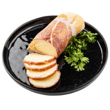 A black TableCraft melamine serving plate holds a log of smoked cheese wrapped in prosciutto, with several slices fanned in front. Fresh green parsley garnishes the plate. The background is plain white.