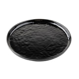 A round, flat black melamine serving plate with a glossy, slightly rippled surface and a smooth, raised edge. The plate sits on a white background, and its reflective finish highlights the textured pattern.