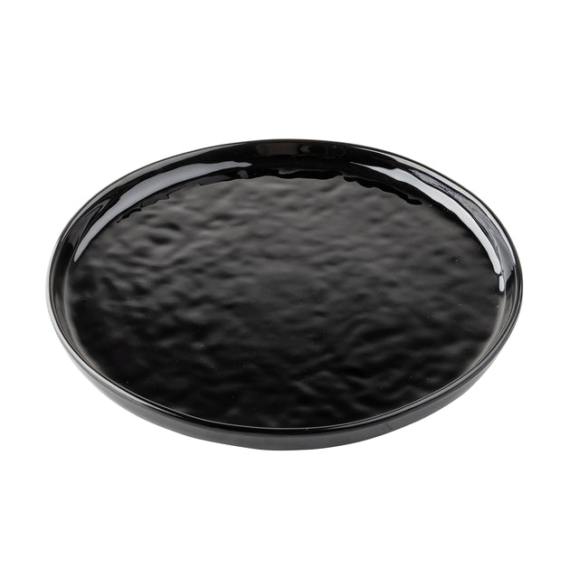 A round, flat black melamine serving plate with a glossy, slightly rippled surface and a smooth, raised edge. The plate sits on a white background, and its reflective finish highlights the textured pattern.