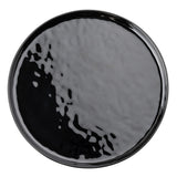 A round, glossy TableCraft black melamine plate from the Ridge Collection, with a slightly wavy, textured surface. Light reflects across the plate, creating irregular highlights and depth. The image is shot top-down against a white background.