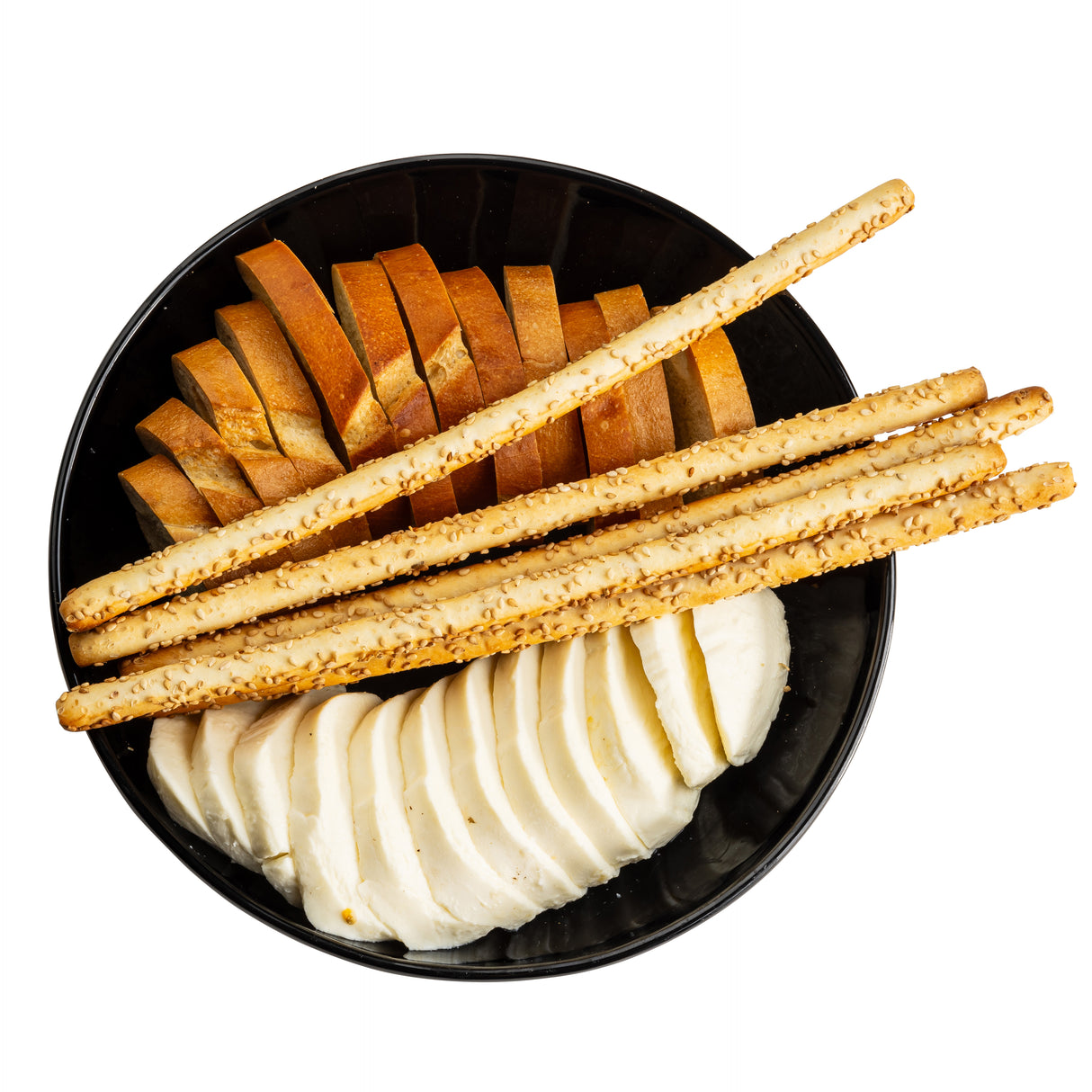 A black melamine serving bowl from the Ridge Collection contains neatly arranged sections of brown bread slices, five sesame breadsticks, and round slices of white cheese, all set against a white background.