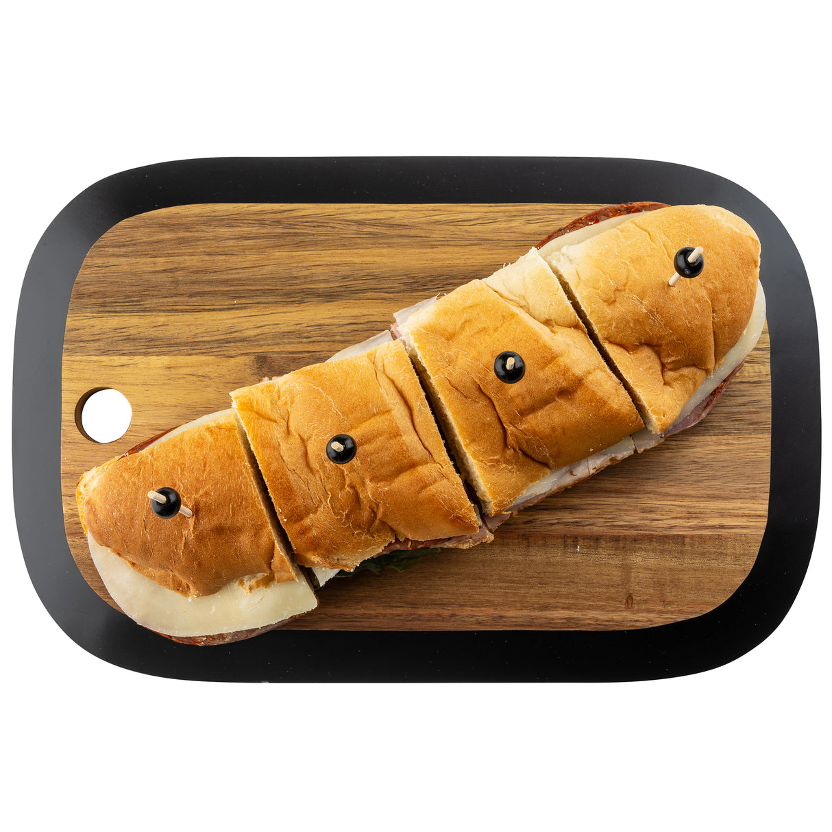 A sub sandwich cut into four pieces, each secured with a black olive on top, is placed on a TableCraft Acacia Collection rectangular serving board with rounded edges and a small hole in one corner, set against a white background.