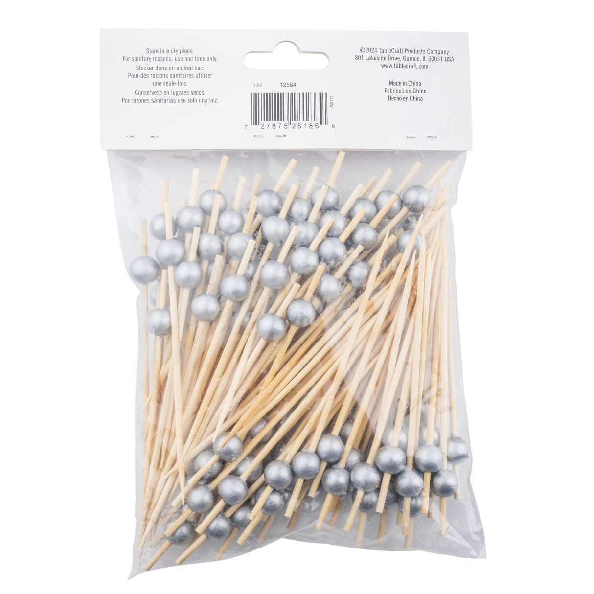 A clear plastic bag filled with TableCraft Ball Picks, each bamboo pick topped with a shiny silver ball. The bag is sealed and has a white label at the top with barcode and product info in multiple languages. The picks are neatly arranged, points facing downward.