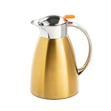 A gold-colored TableCraft stainless steel coffee carafe with a shiny silver lid and spout, an orange push button on top, and a curved handle. The modern, sleek design stands out against the plain white background.