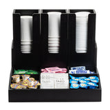 A Coffee Condiment Organizer with cup/lid holders, this black organizer neatly arranges white paper cups, tea bags, sugar packets, creamer cups, and sweeteners into separate compartments for easy access.
