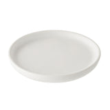 A plain, round, white ceramic serving plate with slightly raised edges is shown against a white background. The plate appears empty and clean, with smooth, simple lines and a minimalist design.