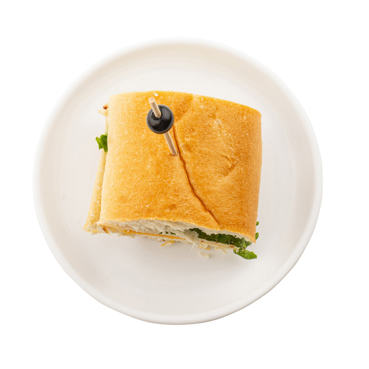 A sandwich on a round white melamine Serving Plate, photographed from above. The sandwich features a thick piece of baguette, visible lettuce, and is held together with a wooden pick topped by a black olive. The background is plain white.