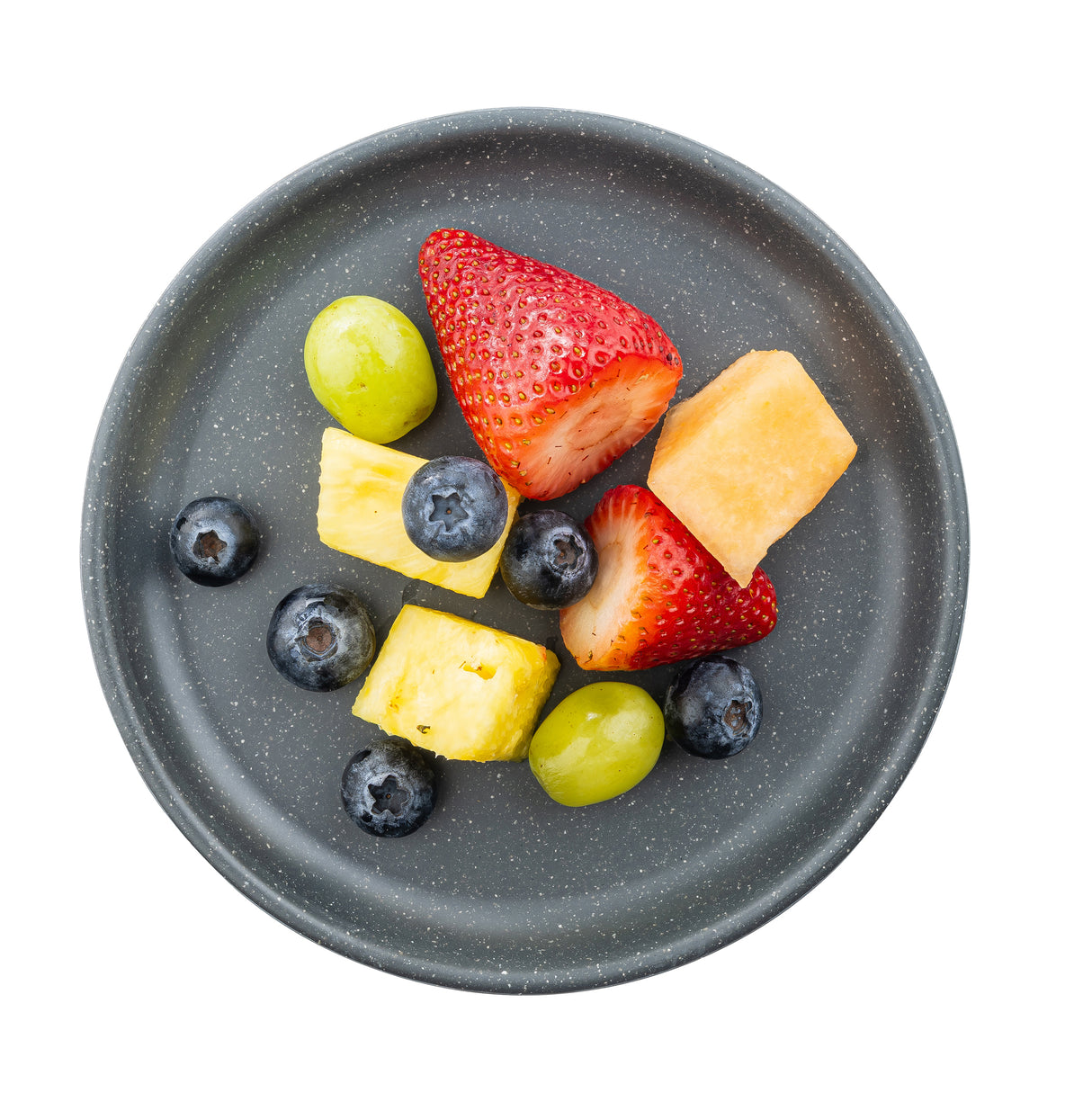 A gray speckled Terra Collection Serving Plate holds a small assortment of fruit: two strawberries, green grapes, blueberries, pineapple cubes, and cantaloupe cube, all viewed from above and isolated on a white background.